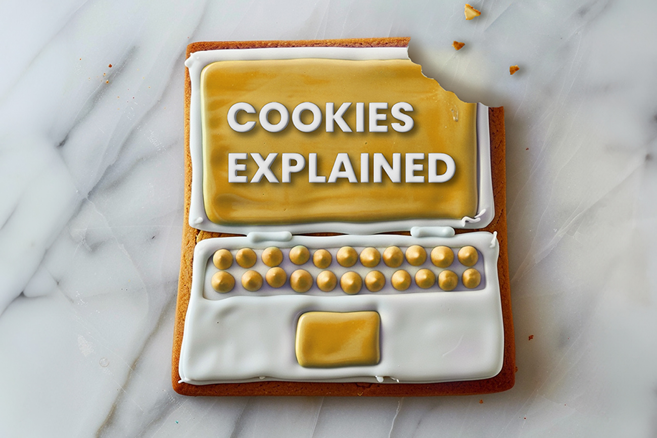 A decorated cookie designed to look like a computer screen displaying the text "that's the way cookies explained" above a keyboard and mouse, set on a marble surface.